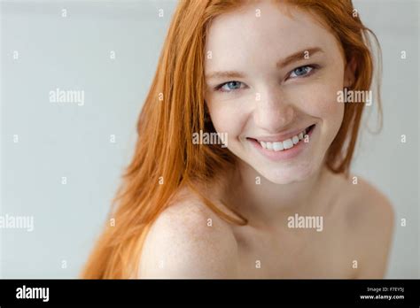 Portrait Of A Smiling Redhead Woman Looking At Camera On Gray