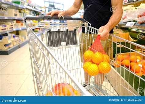 Man Customer Puts Grid Of Oranges In Grocery Cart In Supermarket Store