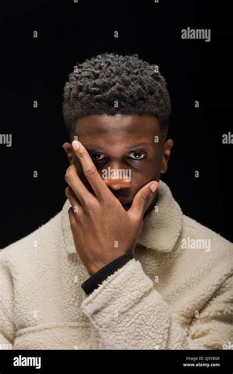 Black Man With Short Curly Hair Covering Half Of The Face With Hands On