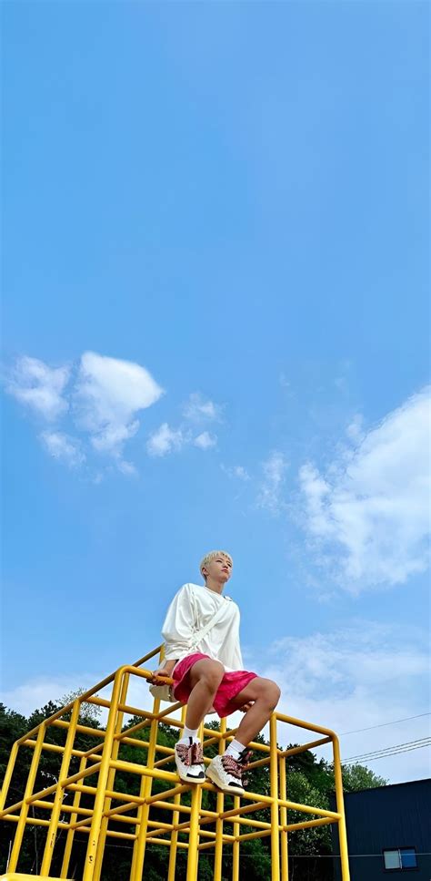 A Man Sitting On Top Of A Yellow Metal Structure Next To A Blue And