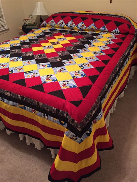 A Bed With A Red Yellow And Black Bedspread On Top Of It