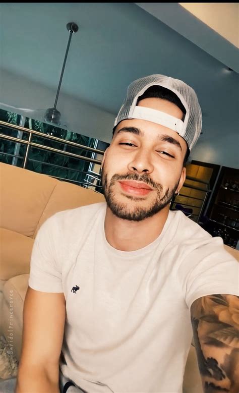 A Man Sitting On Top Of A Couch Wearing A White Shirt And Grey Baseball Cap