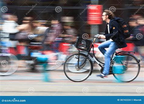 Homem Que Monta Uma Bicicleta Abaixo Da Rua Amsterdão Imagem de Stock