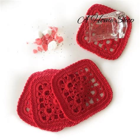 Three Crocheted Coasters Are Sitting On A Table Next To Some Cotton Balls