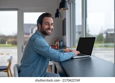 man sideways camera laptop smiling camera stock photo