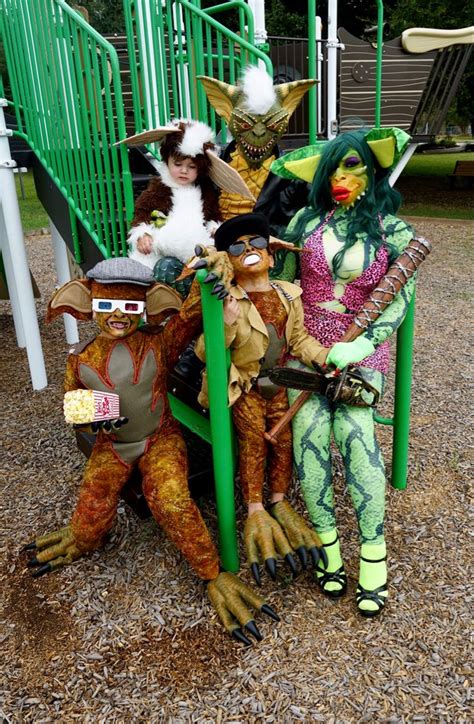 Three People Dressed Up In Costumes Sitting On A Playground Bench With