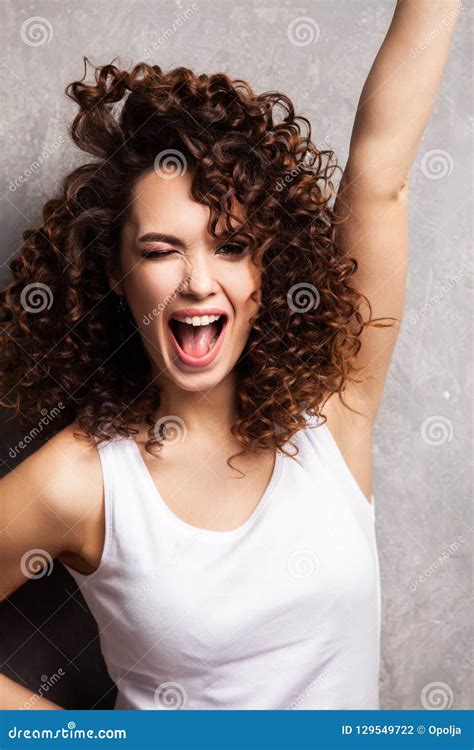 Portrait Of Beautiful Cheerful Girl With Flying Curly Hair Smiling