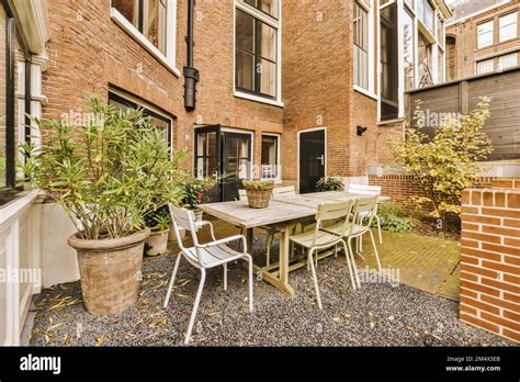 A Patio With Chairs Table And Potted Plants On The Ground In Front Of