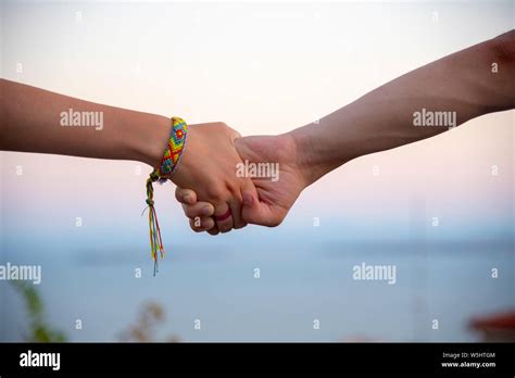 Two Hands Male And Female Holding Each Other Tightly On A Blurred Light Background On The