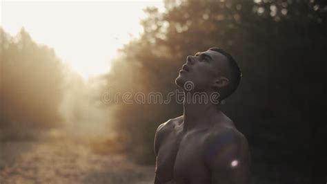 Muscular Handsome Man With Naked Torso Stands In The Forest And Breathes Deeply Against Dawn