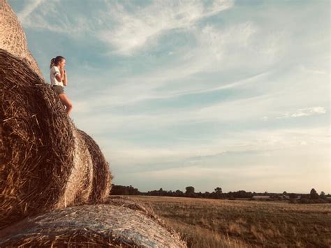 Premium Photo Girl Standing On Hay Bales Against Sky