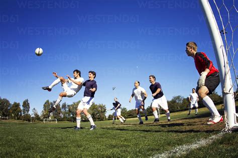 Friends Playing Soccer At Field Stock Photo