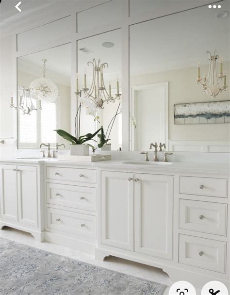 A White Bathroom With Double Sinks And Large Mirrors On The Wall Above