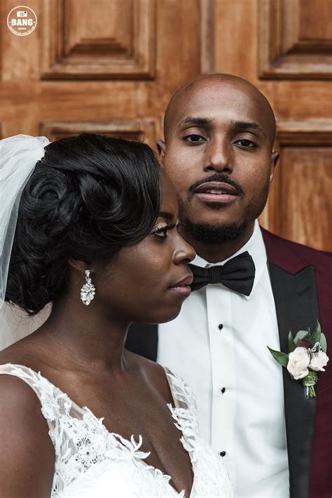 A Bride And Groom Standing Together In Front Of A Wooden Door