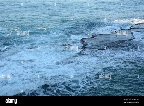 Sea Waves Crashing On The Rocks With White Foam Swirling Frothy Foamy