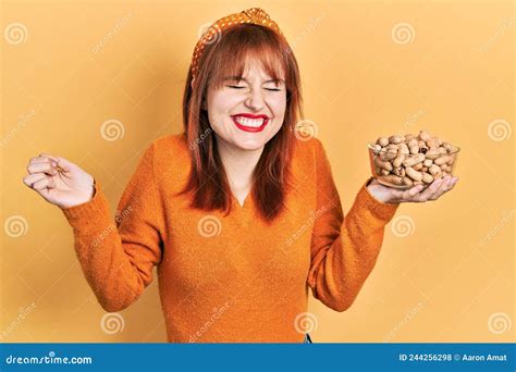 Redhead Young Woman Holding Peanuts Screaming Proud Celebrating Victory And Success Very