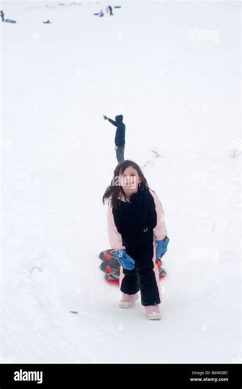 Young Girl Smiling And Pulling Sled Up Hill In Snow Stock Photo Alamy