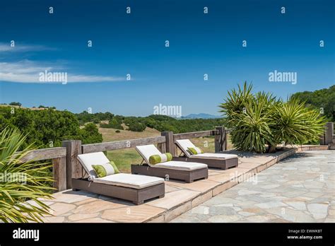 Modern Chaise Lounge Chairs With Pillows On Flagstone Patio Deck Stock