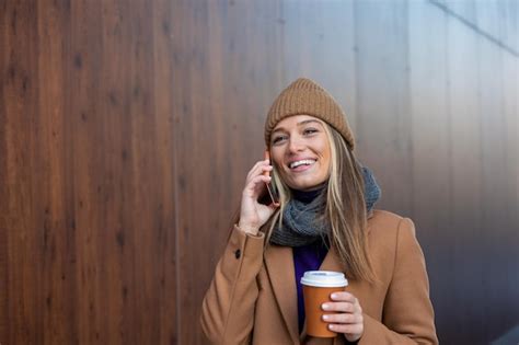 Hermosa mujer yendo a trabajar con café caminando cerca del edificio de