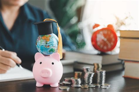 Graduation Cap With Globe On Pink Piggy Bank With Stack Of Coins