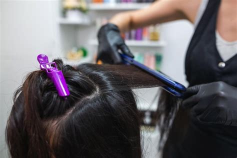 Premium Photo | Hairdresser using a hair straightened to straighten the ...
