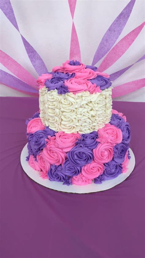 a multi - colored cake with pink, purple and white frosting on a table