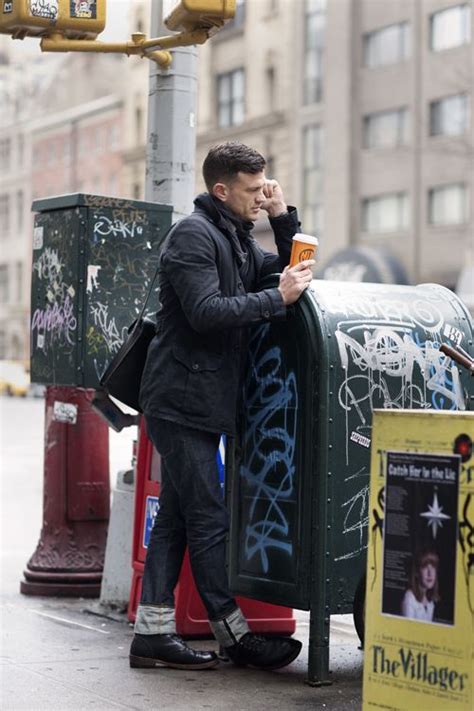 A Man Standing Next To A Mailbox With Graffiti On It And Holding A Drink