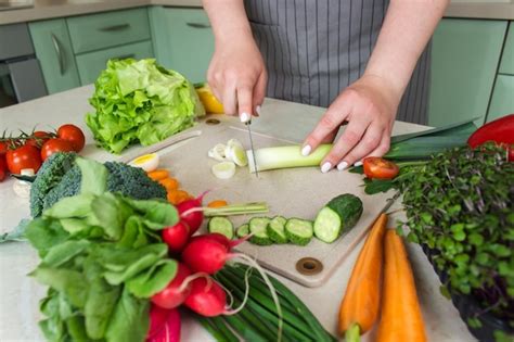 Premium Photo Woman Cutting Fresh Vegetables For Salad In Kitchen