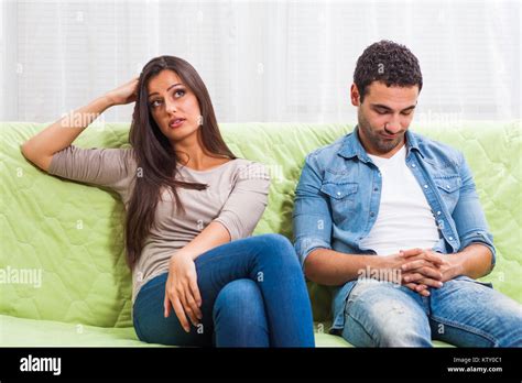 Young Couple Is Sitting On Sofa At Home And They Are Getting Bored