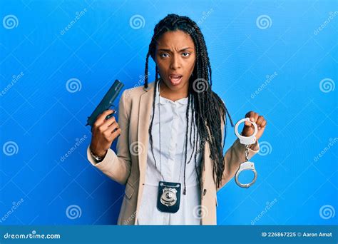 African American Police Woman Holding Gun And Handcuffs Clueless And