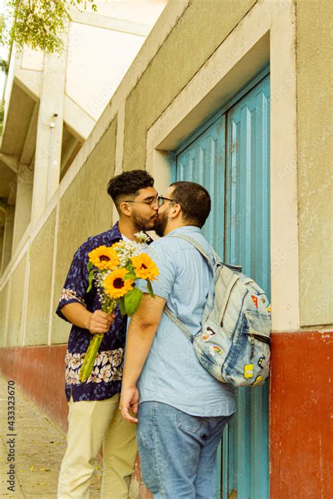 Pareja de novios gay besándose en la calle con flores amarillas en la mano Stock Photo Adobe Stock