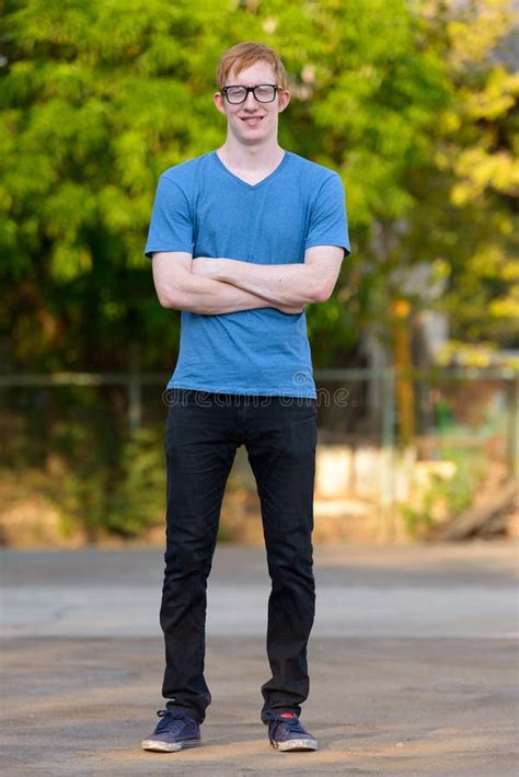 Full Body Shot Of Happy Nerd Man With Red Hair Smiling In The Park