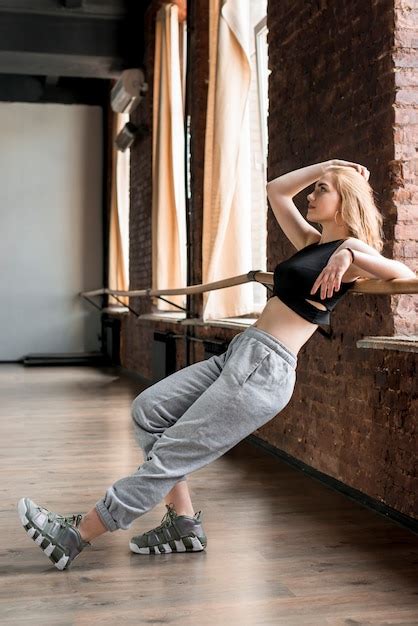 Blonde Jeune Femme Se Penchant Sur La Barre Dans Le Studio De Danse Photo Gratuite