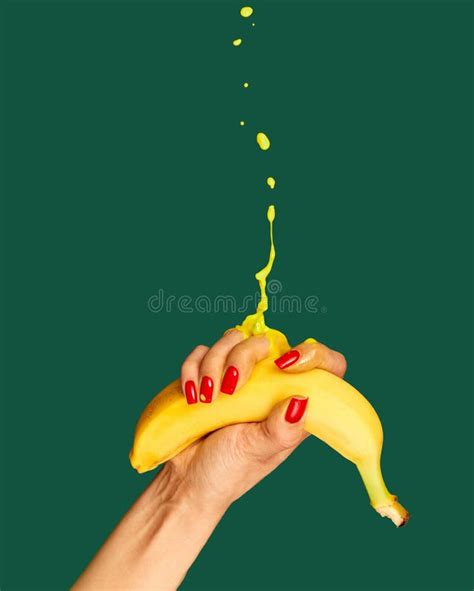 Female Hand With Bright Manicure Squeezes Banana Over Green Background