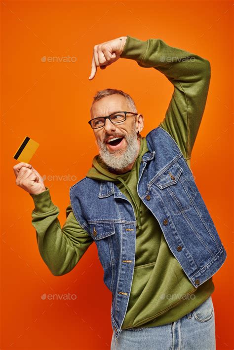 Cheerful Attractive Mature Male Model In Stylish Denim Vest Pointing At