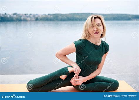 Young Blond Woman Wearing Green Overall With Bare Feet Doing Yoga Pose