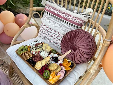 A Tray Of Fruit And Cheese On A Wicker Chair With Balloons In The