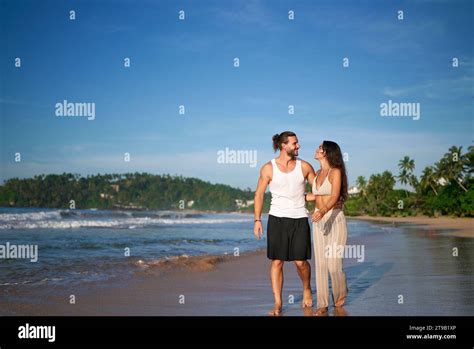 Romantic Couple Strolls On Tropical Beach At Sunset Man And Woman In