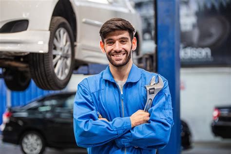 Portrait Of Smiling Male Mechanic Technician Holding Wrench In Arms