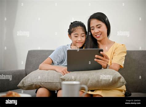 Feliz mamá asiática y su hija joven se relaja en la sala de estar