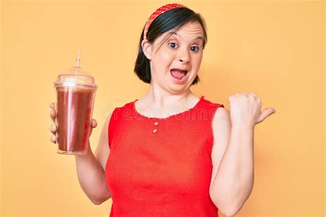 Brunette Woman With Down Syndrome Holding Glass Of Smoothie Pointing