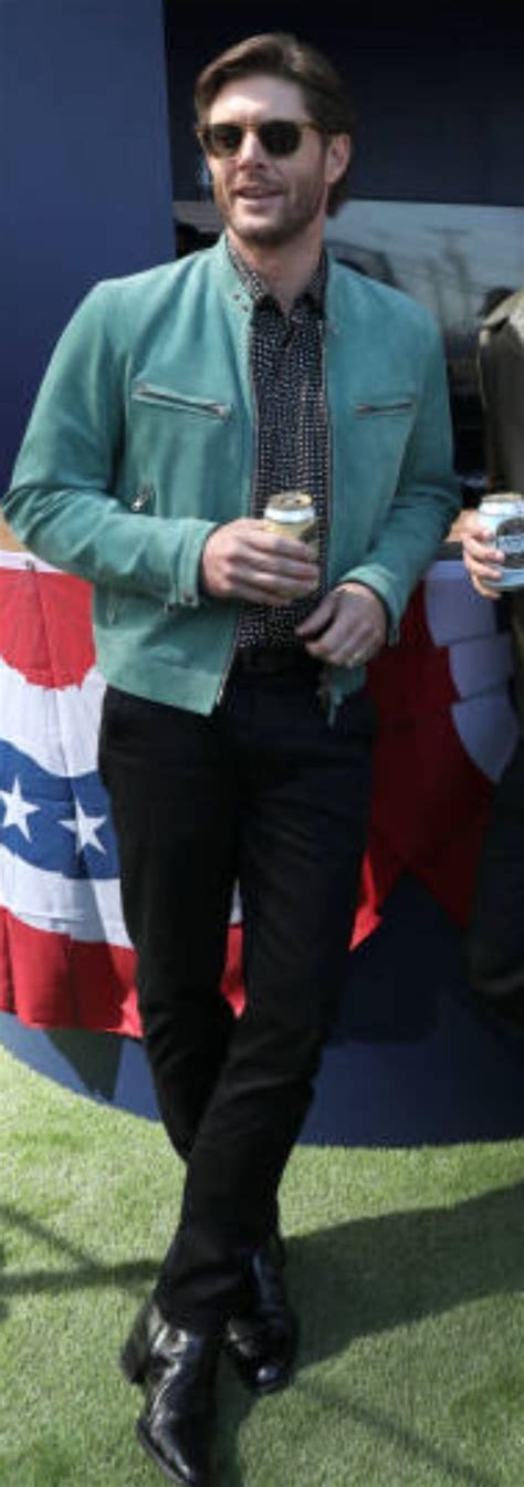 A Man In A Green Jacket And Tie Standing Next To An American Flag