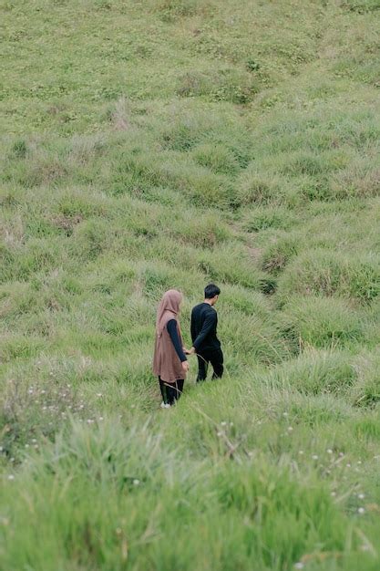 Premium Photo A Man And A Woman Walk Through A Field Of Grass