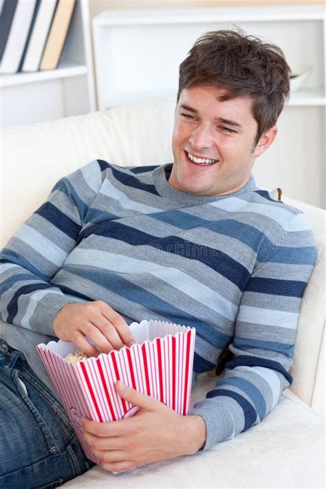 Cheerful Young Man Eating Popcorn On The Sofa Royalty Free Stock Images - Image: 16263039