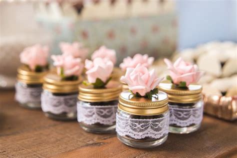 Small Jars Filled With Pink Flowers On Top Of A Wooden Table