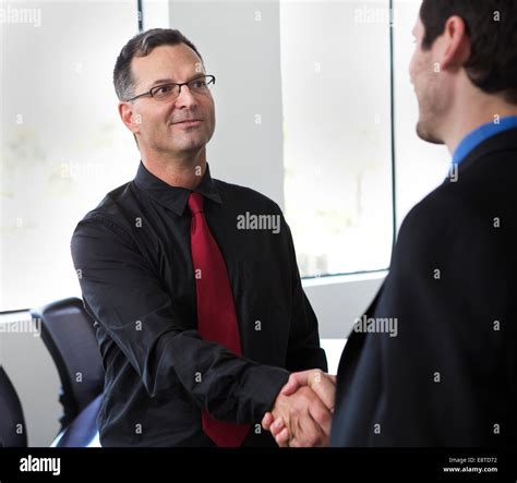 Businessmen shaking hands in office Stock Photo - Alamy