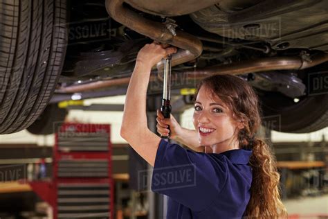 Portrait of female auto mechanic working underneath car - Stock Photo ...
