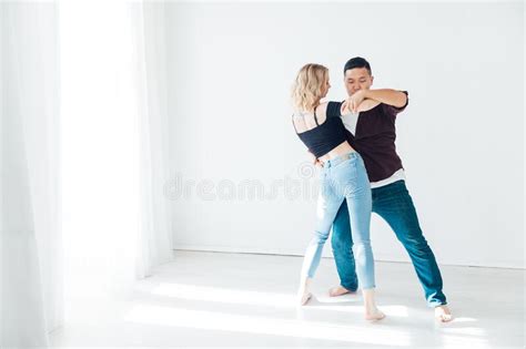 A Woman And A Man Dancing To The Music Of A Bachata In A White Hall