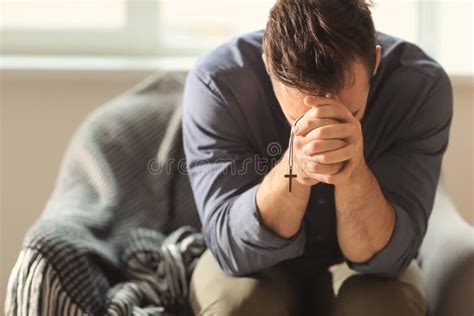 Hombre Joven Religioso Que Ruega A Dios En Casa Imagen De Archivo