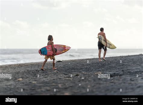 Bali Indonesia Man And Women Holding A N Surfboard On The Beach